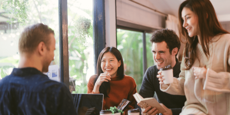 A diverse group of employees gathered around a table, enjoying coffee and engaging in conversation.