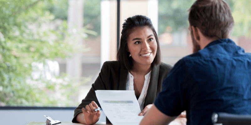 A manager and employee engaged in conversation while seated at a table.